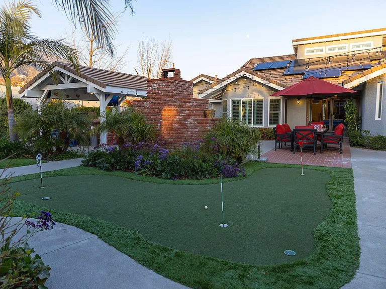 Discover your backyard sanctuary with a fun putt-putt golf area, a covered outdoor kitchen, and an inviting dining space that seats 6_perfect for unforgettable gatherings and relaxing days under the open sky.