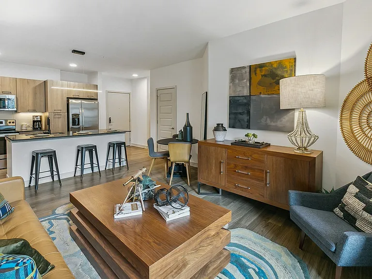 Relax in a beautifully curated living area featuring bold decor, warm wood finishes, and seamless flow to the kitchen.