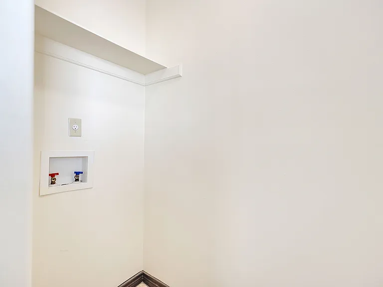 A clean white wall with a toilet and sink, located in the La Joya Apartments in Laredo, Texas