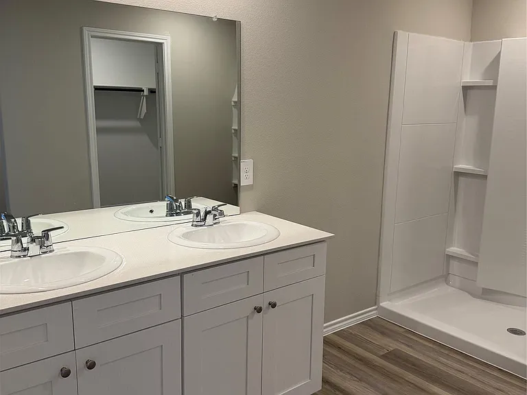 Bathroom featuring a dual vanity with white shaker cabinetry and a white countertop