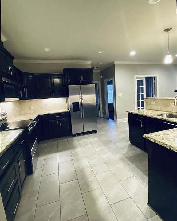 Kitchen well-equipped with recessed lighting, under cabinet lighting, new glass cook-top range, Refrigerator with water and ice in the door, granite countertops, tumbled stone backsplash, & stained cabinets