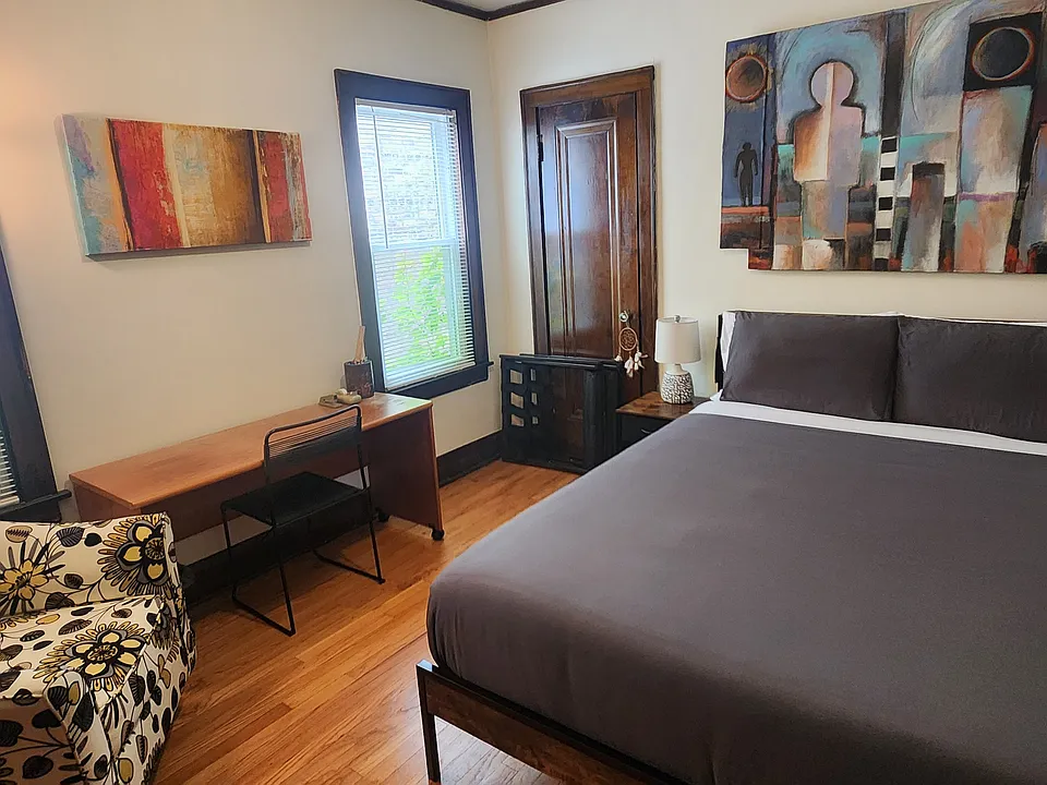 Third Bedroom with new queen-sized bamboo/charcoal/green tea memory foam bed that includes LED lights and a charging station, desk, chair, file cabinet, accent chair, shelf unit, two rugs, two lamps, artwork, and large closet with mirror.