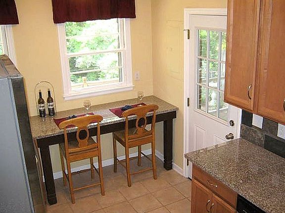 Kitchen includes granite top breakfast bar overlooking yard. New 9-paneled glass/steel door from car