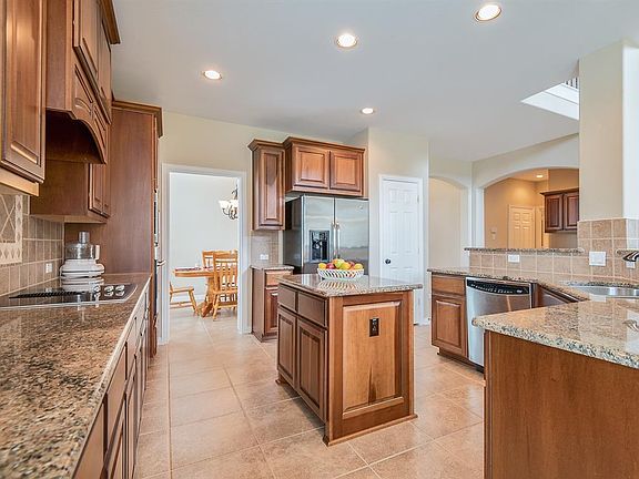 CENTER ISLAND PLUS THREE SIDE WRAP AROUND BREAKFAST BAR MAKE THIS KITCHEN STAND OUT. AMAZING AMOUNT OF COUNTER SPACE MAKING FOR EASE OF FOOD PREP AND ENTERTAINING. AN ABUNDANCE OF GORGEOUS CABINETS AND A LARGE PANTRY COMPLETE THIS KITCHEN.