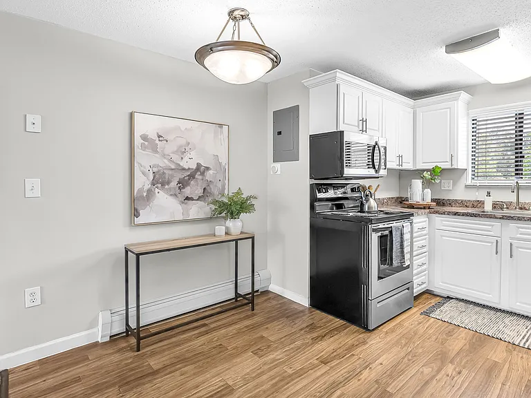 Discover a classic dining space with wood-style floors and a stylish overhead lighting fixture, thoughtfully designed to connect the kitchen and living room seamlessly.