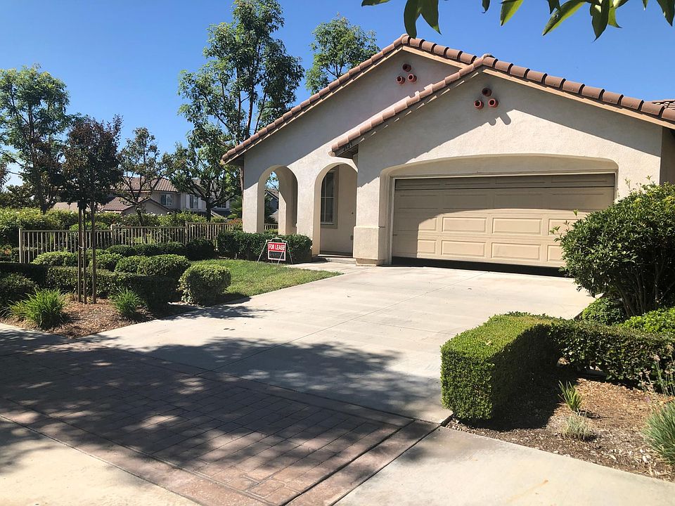 Cozy front porch, green front lawn and a sprawling driveway with a two-car garage