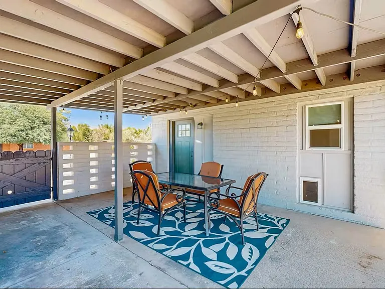 Carport and patio area with table and BBQ.