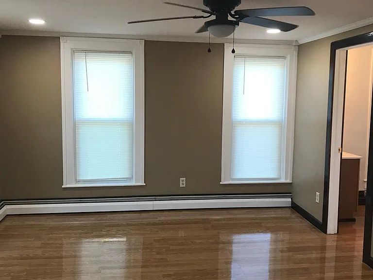 View of living room with overhead light and ceiling fan. Hardwood floors.