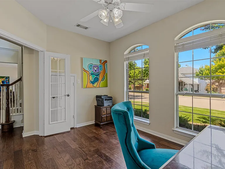 Room featuring wood-finish flooring, a ceiling fan with integrated lighting, and white trim throughout