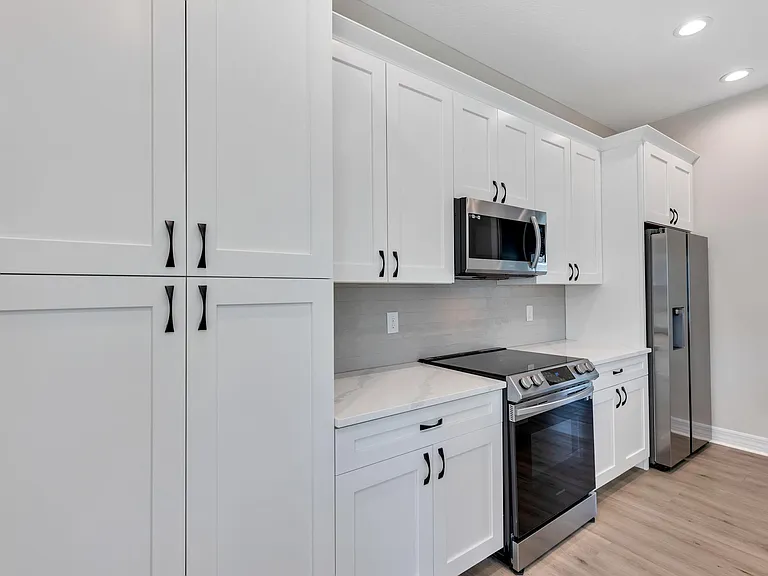 View of kitchen cabinets, fridge, and cooking space. Tons of storage!