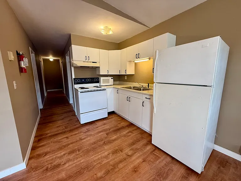 Open kitchen with cabinet storage and included refrigerator, microwave and range.