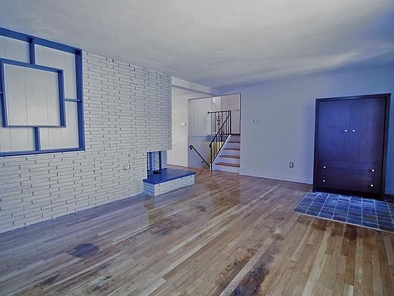 Large living room has hardwood floors, neutral gray walls, and an architecturally decorative firepla