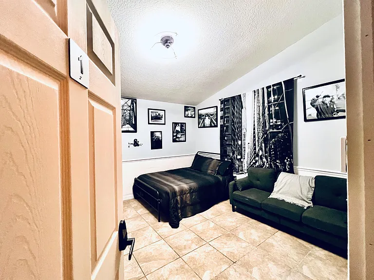 Private bedroom with tile flooring, overhead lighting, and space for a bed and seating area with window curtains.