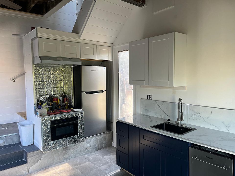 Downstairs kitchen with electric oven, stove, dishwasher, fridge and living space. Enter the garden or deck from here. High ceilings and storage.