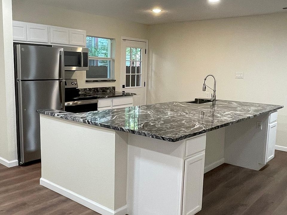 Open concept living room and kitchen. Dual ceiling fans, LED lights, stainless steel refrigerator, stove, microwave, dishwasher, farm house sink. Inset electrical outlets for charging wireless devices. Commercial grade luxury vinyl plank throughout.