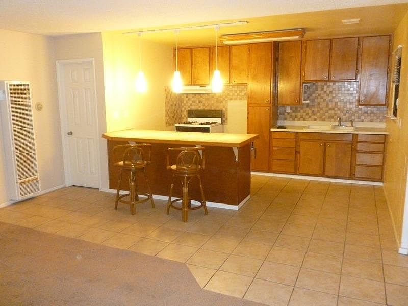Island kitchen with marble countertop, stove and refrigerator. Bars stools. New lightning.