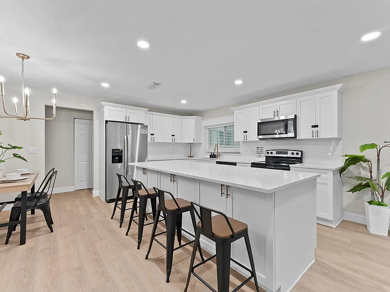 Spacious kitchen with a large island breakfast bar, white cabinetry, and stainless steel appliances for everyday cooking.