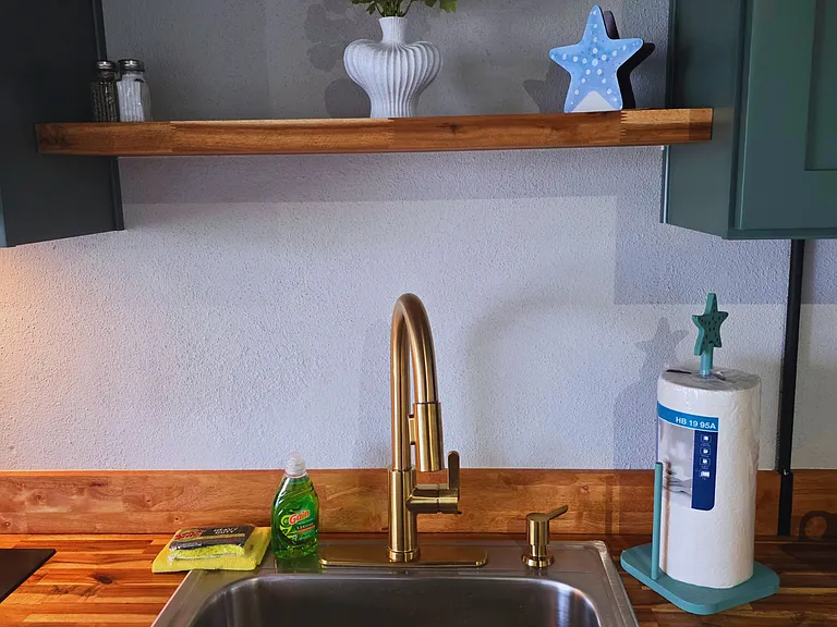 Gold-finish sink with dish soap and paper towels for added convenience.