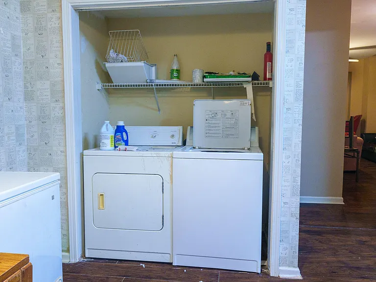 Dedicated laundry nook with a full-size washer and dryer plus a built-in shelf for detergents and supplies.