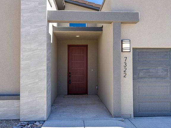 Modern house entrance with a red front door, light-colored exterior walls, and the number 7322 displ