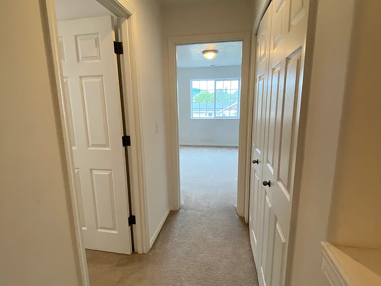 Hallway looking into primary bedroom. Laundry closet on right. Bedroom #2 on left.