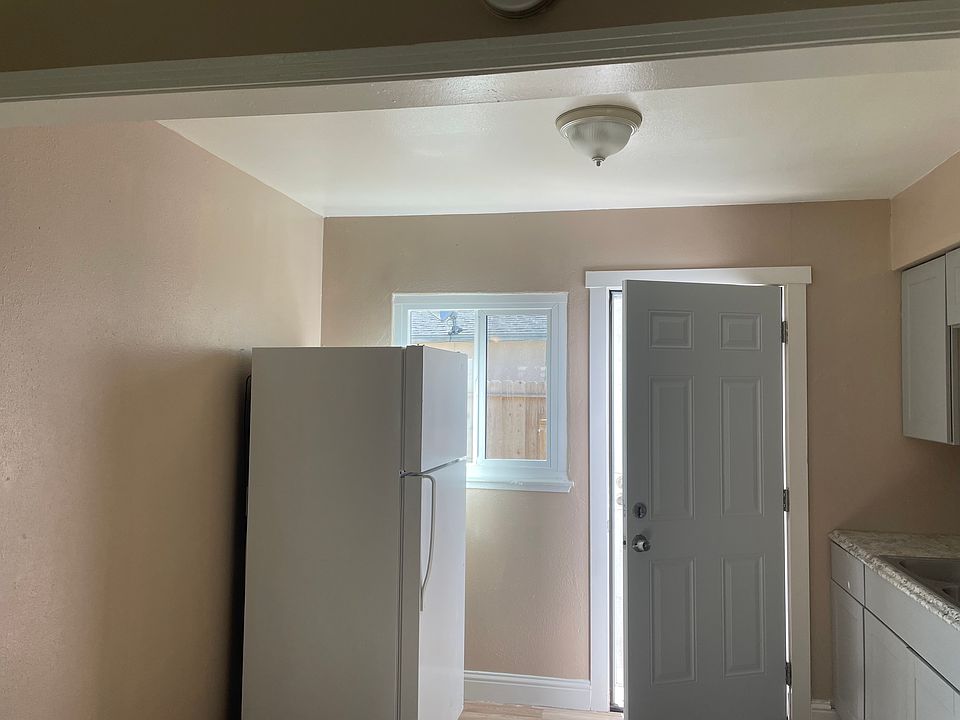 Refrigerator and kitchen with entrance to enclosed backyard.