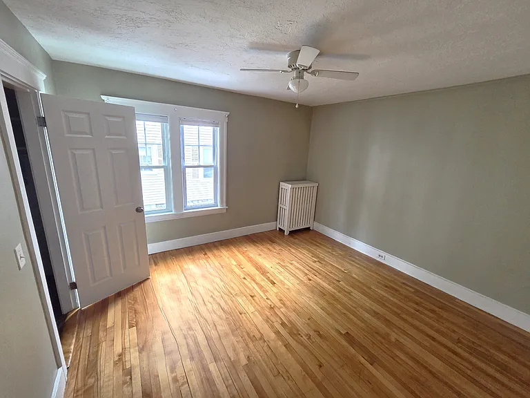 Spacious second bedroom with closet and ceiling fan.
