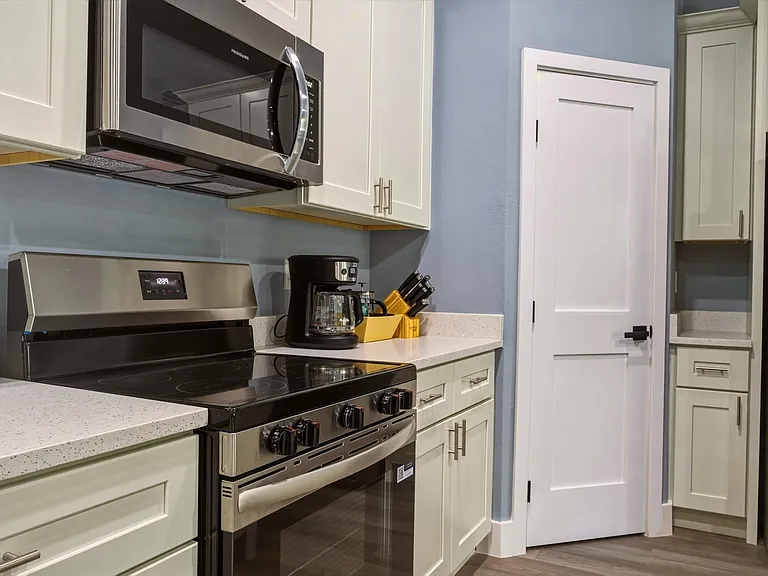 Updated kitchen with stainless steel range and microwave, ample shaker cabinetry, and generous countertop workspace.