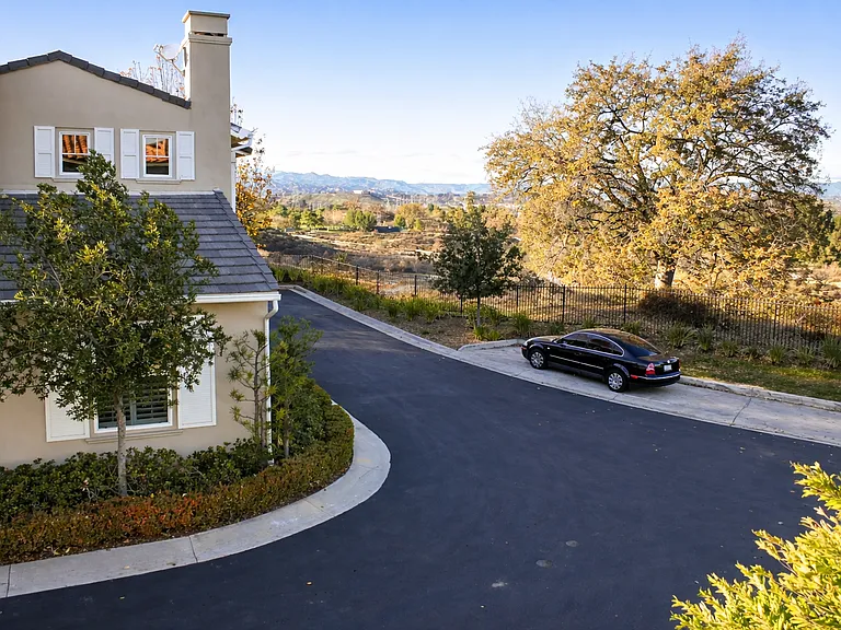 View from bedroom with French doors open to private balcony overlooking quiet street and scenic hills