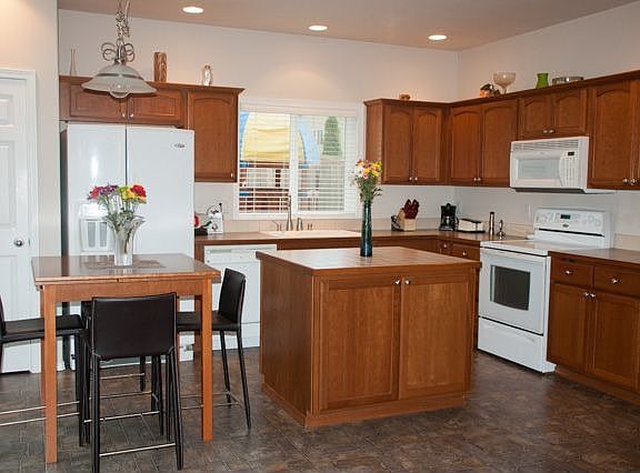 The kitchen is adorned with Cherry Cabinets and equiped with built-in microwave, glass cooktop, pantry, prepping island and eating nook.