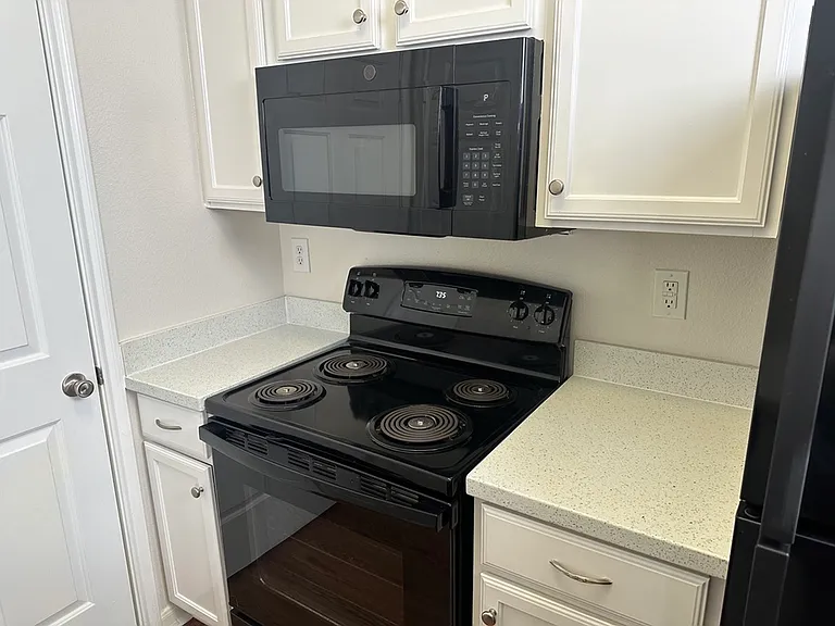 Sleek modern kitchen with black appliances, pristine white cabinetry, and quartz countertops. Sleek modern kitchen with black appliances, pristine white cabinetry, and quartz countertops.