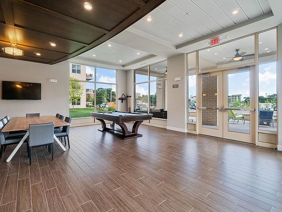 Community room with pool table and floor to ceiling windows to enjoy outside events and bright sunlight during the daytime.