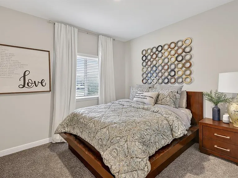 Carpeted room with a window featuring horizontal blinds and white curtains