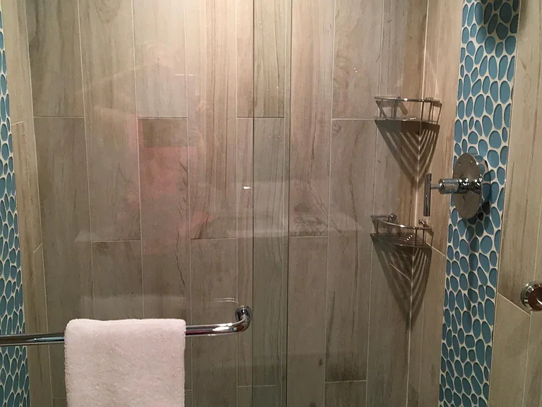 Inlay tile within floor to ceiling shower creates a waterfall look.