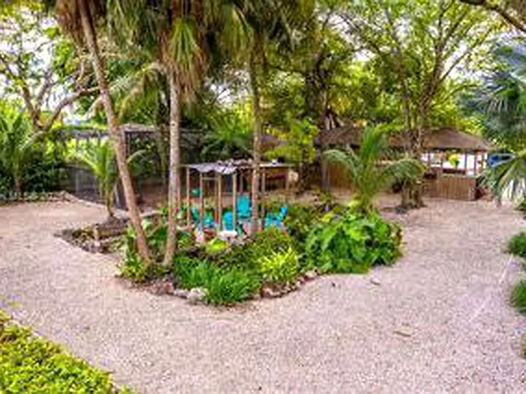 Beautiful tropical garden grounds with mature palms, winding paths and peaceful shaded seating areas throughout the estate.