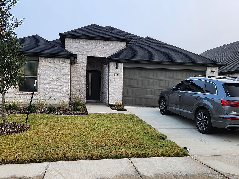 Front view of the house with two-car garage and freshly landscaped yard.