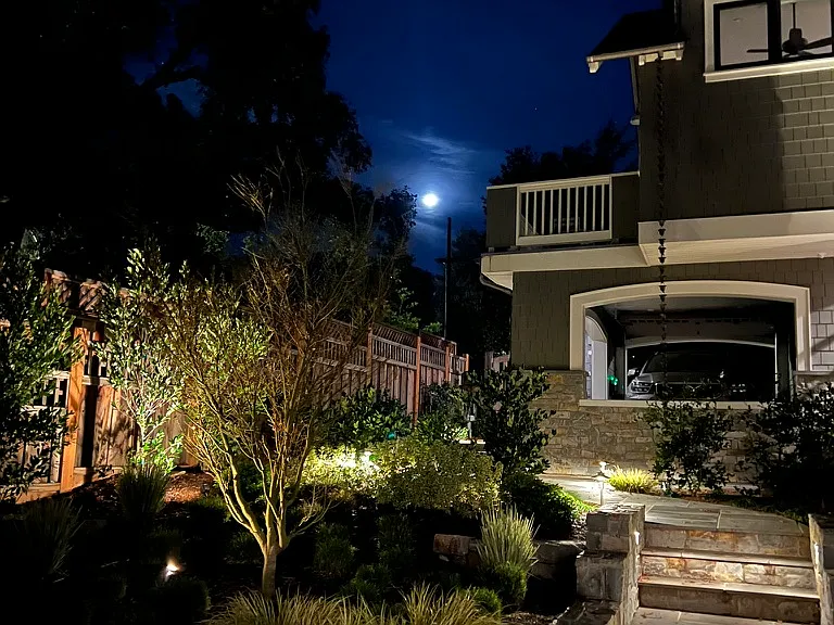 Exterior view of the Carriage House Skydeck from the lower backyard in the evening.