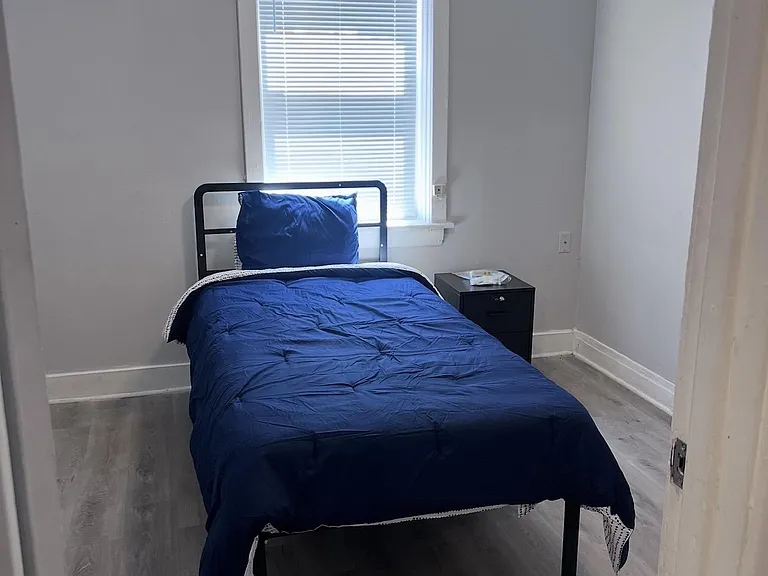 Private bedroom with a window, ceiling fan, and durable wood-look flooring, furnished with a bed and nightstand.