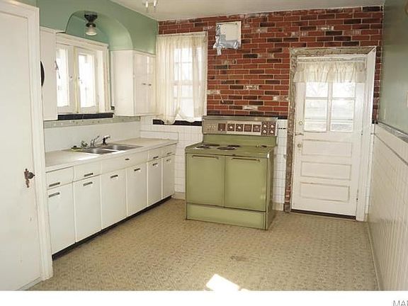 Kitchen with exposed brick wall, ceiling fan, pantry, garbage disposal and entrance to back covered 