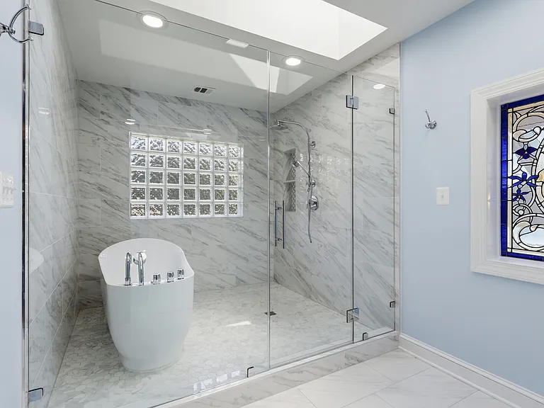 Marble bath: soaking tub, glass shower, skylight.