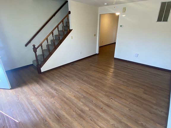 Living room with newer luxury vinyl plank flooring and a ceiling fan. Stairs to the 2 bedrooms and full bath and the eat-in kitchen and half bath are to the right.