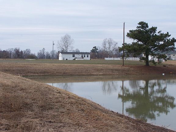 View of home in back with deck and pond