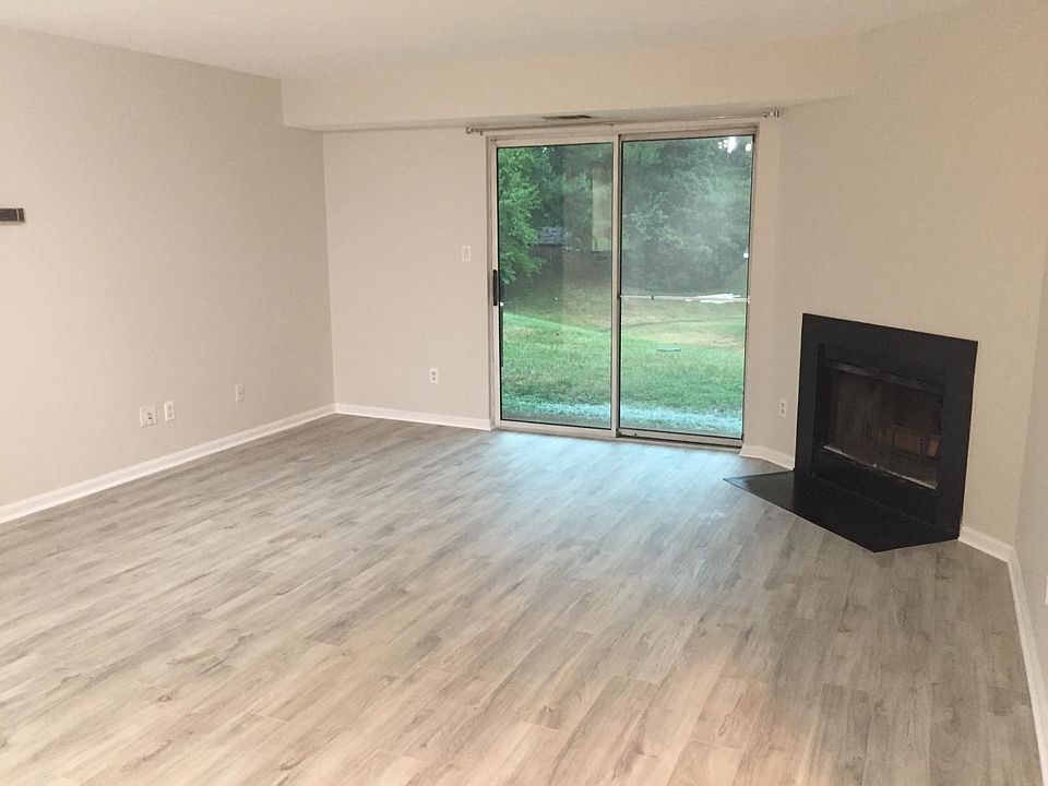 Living room with wood burning fireplace. Sliding glass doors offer easy access to patio and greenspace.