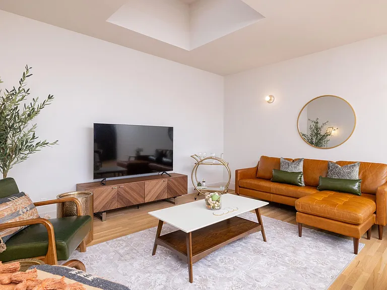 Inviting living room with a comfy couch, two chairs, flat-screen TV, and a stylish bar cart_perfect for relaxing or entertaining.