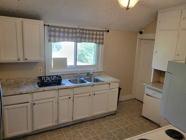 Kitchen features ample cabinet storage, generous countertop space, and a double-basin sink set below a window.