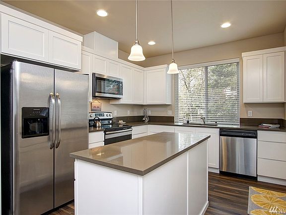 Beautiful stainless steel appliance package features microwave with fan that vents to the outside!!  Check out those gorgeous quartz countertops and cool pendant lighting!