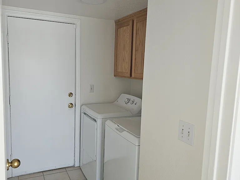 Functional laundry space featuring a modern washer and dryer set with convenient overhead cabinetry.