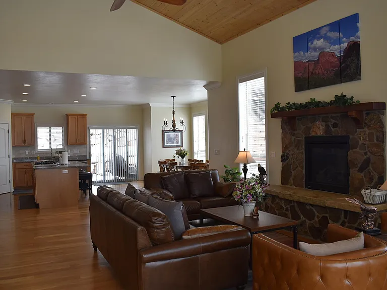 Open, spacious Great Room where large windows invite natural light and showcase mountain views. Relax by the fireplace or gather around the wooden table that seats seven, thoughtfully set in a cozy nook for meals and memorable moments.