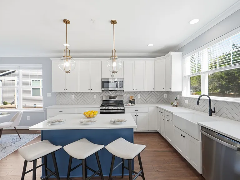 Chef's kitchen with island, farmhouse sink, herringbone backsplash, gas range, and breakfast nook.