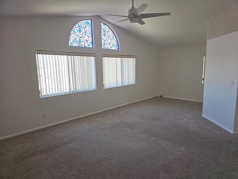 Natural light through the arch windows, illuminates this primary bedroom room with vaulted Ceiling